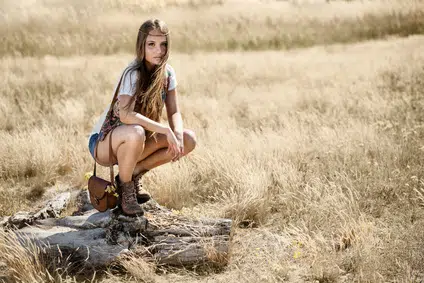 Beautiful hippy girl sitting on a tree stump at midday